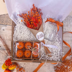 a pumpkin themed gift box with set of 6 mini pumpkin candles, a glass vase with orange ribbon and a mini bunch of burnt orange dried flowers.