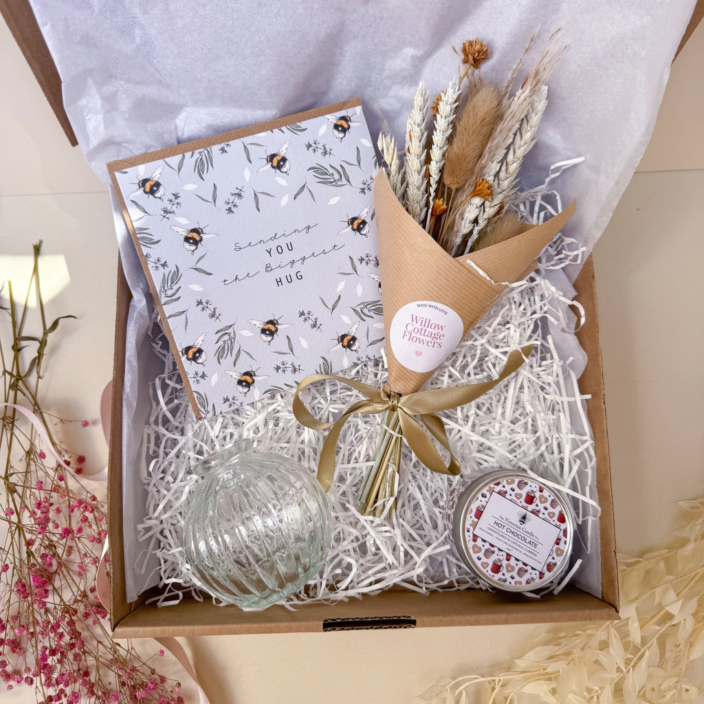 Gift set with card, flowers, and decorative items in a box