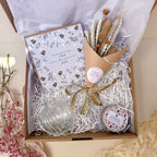 Gift set with card, flowers, and decorative items in a box