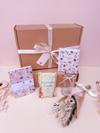 Gift box with a bow, birthday card, and birthday themed gifts on a light pink background