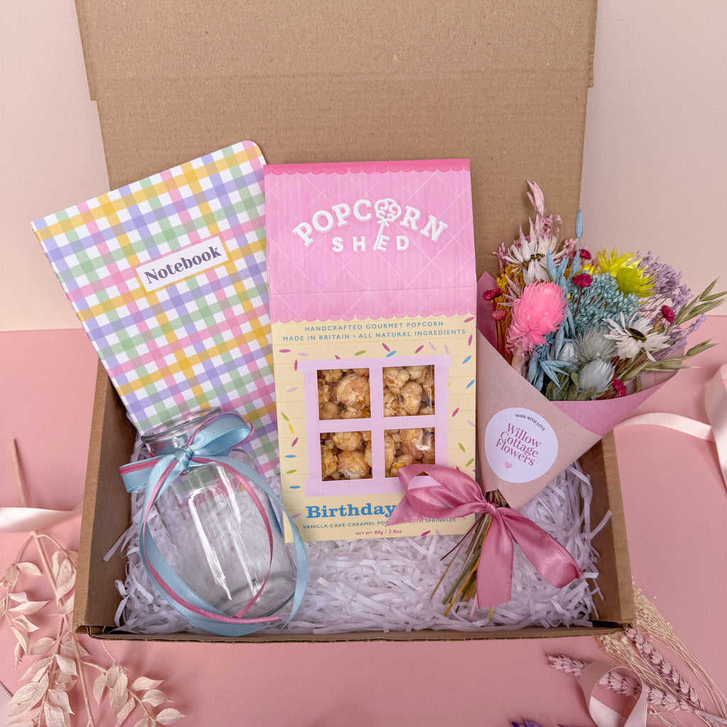 birthday gift box with dried flowers, birthday cake popcorn, glass vase and gingham notebook