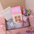 Gift box for birthday with popcorn, notebook, and flowers on a pink background