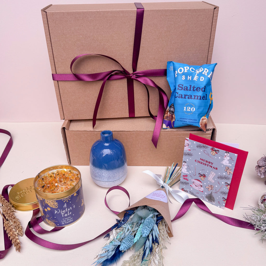 Gift box with festive items including a candle, card, and salted caramel popcorn bag