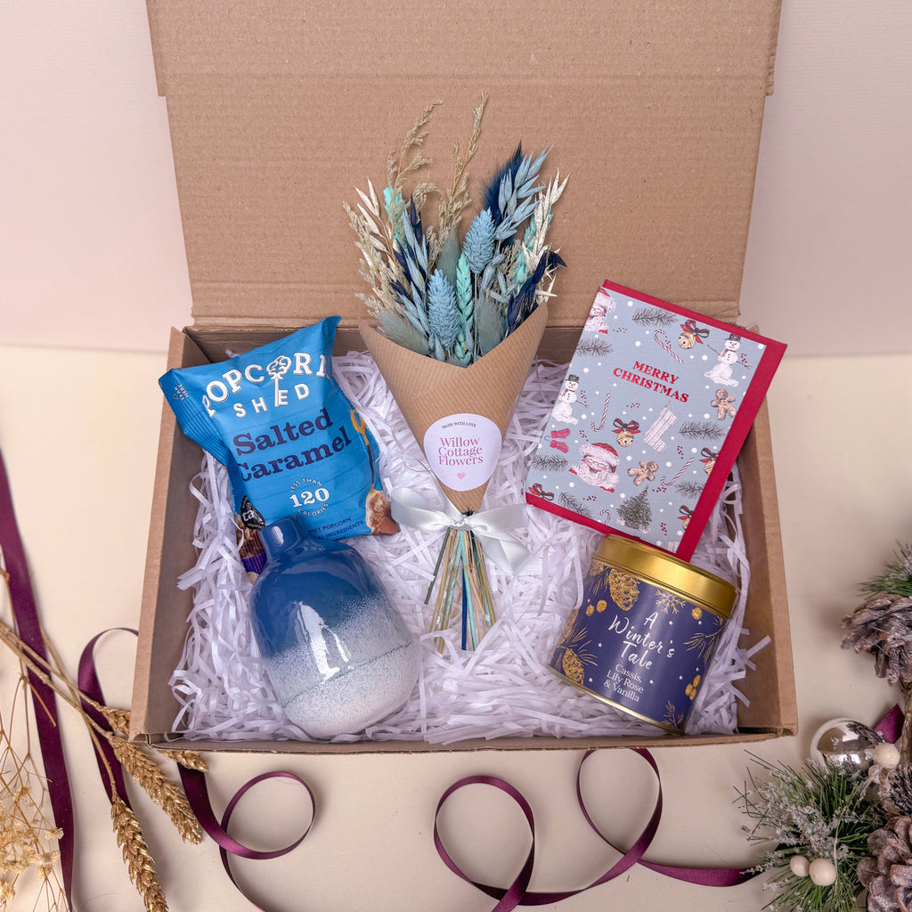Gift box with a bouquet, card, and other christmas items on a light background