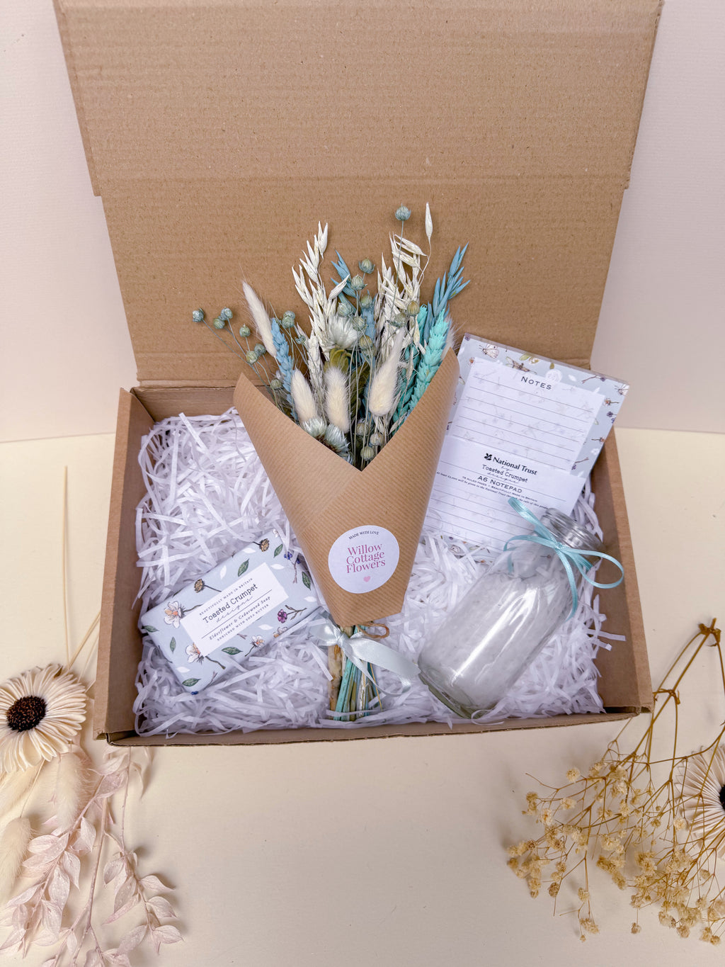 Gift box with a bouquet of flowers, a vase, notebook and soap bar.