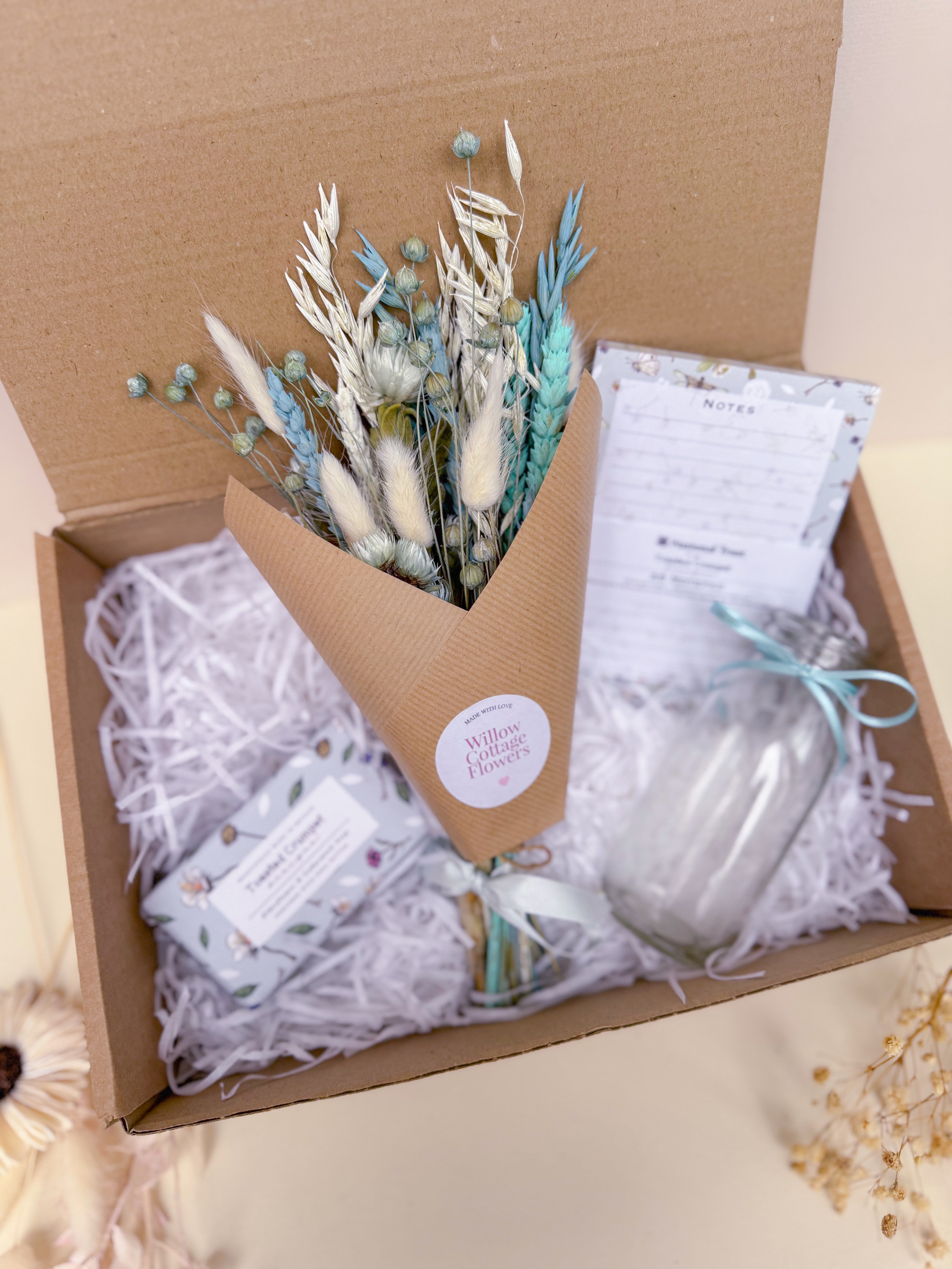 Bouquet of wrapped blue dried flowers in a gift box with home decor items