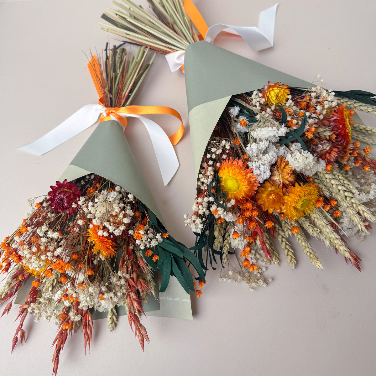 set of two burnt orange, green and white dried flower bouquets wrapped in green paper