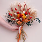 burnt orange bouquet of dried flowers being held against a cream background
