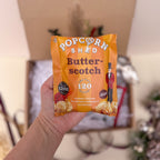Hand holding a Popcorn Shed Butter-scotch popcorn packet 