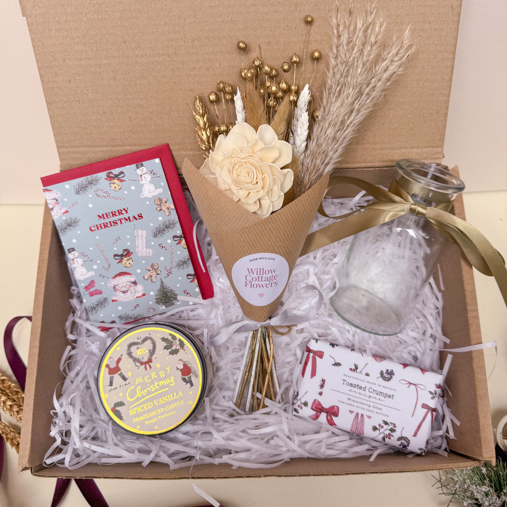 Gift box with flowers, candles, and other festive items on a light background