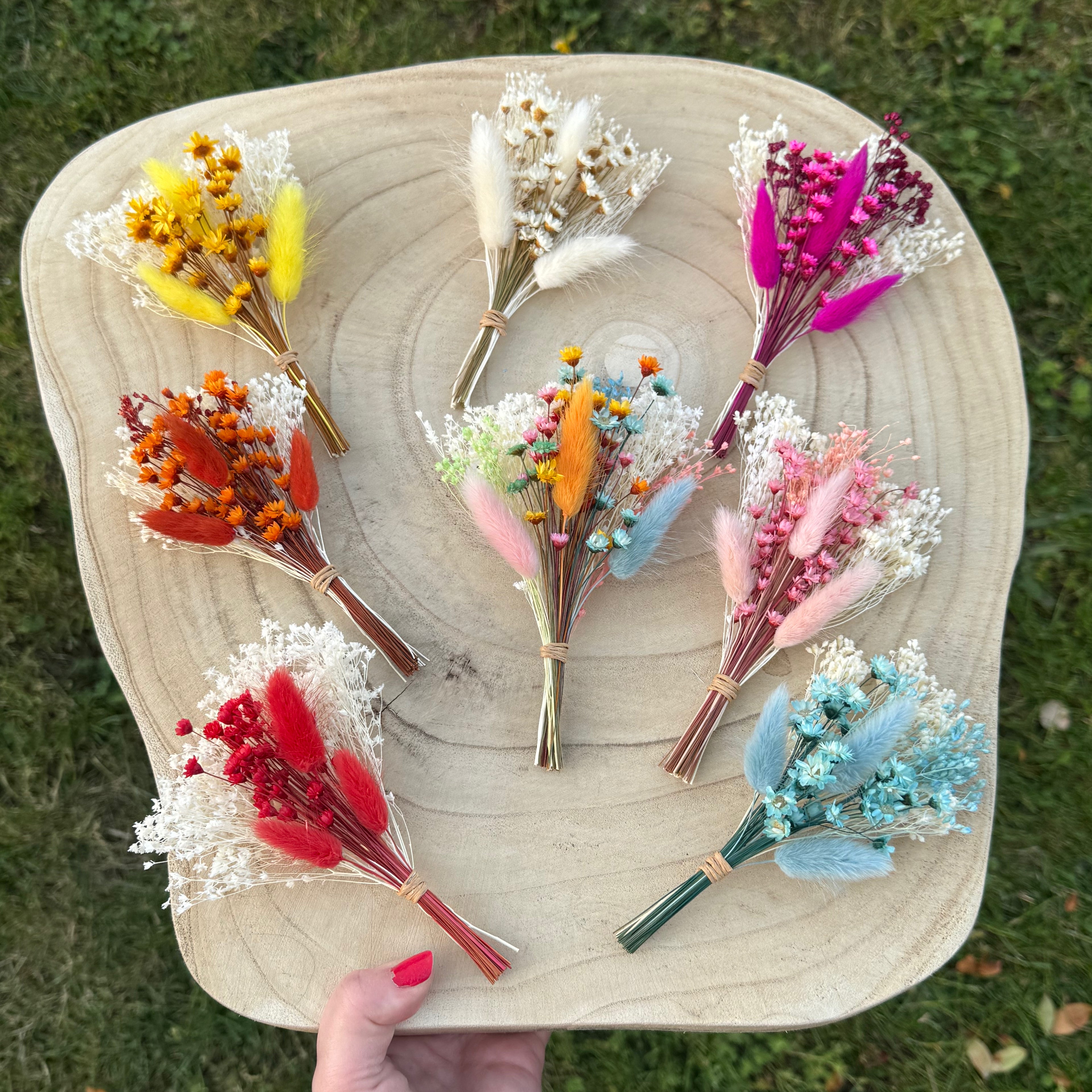 dried flower buttonholes in various colours on wood display