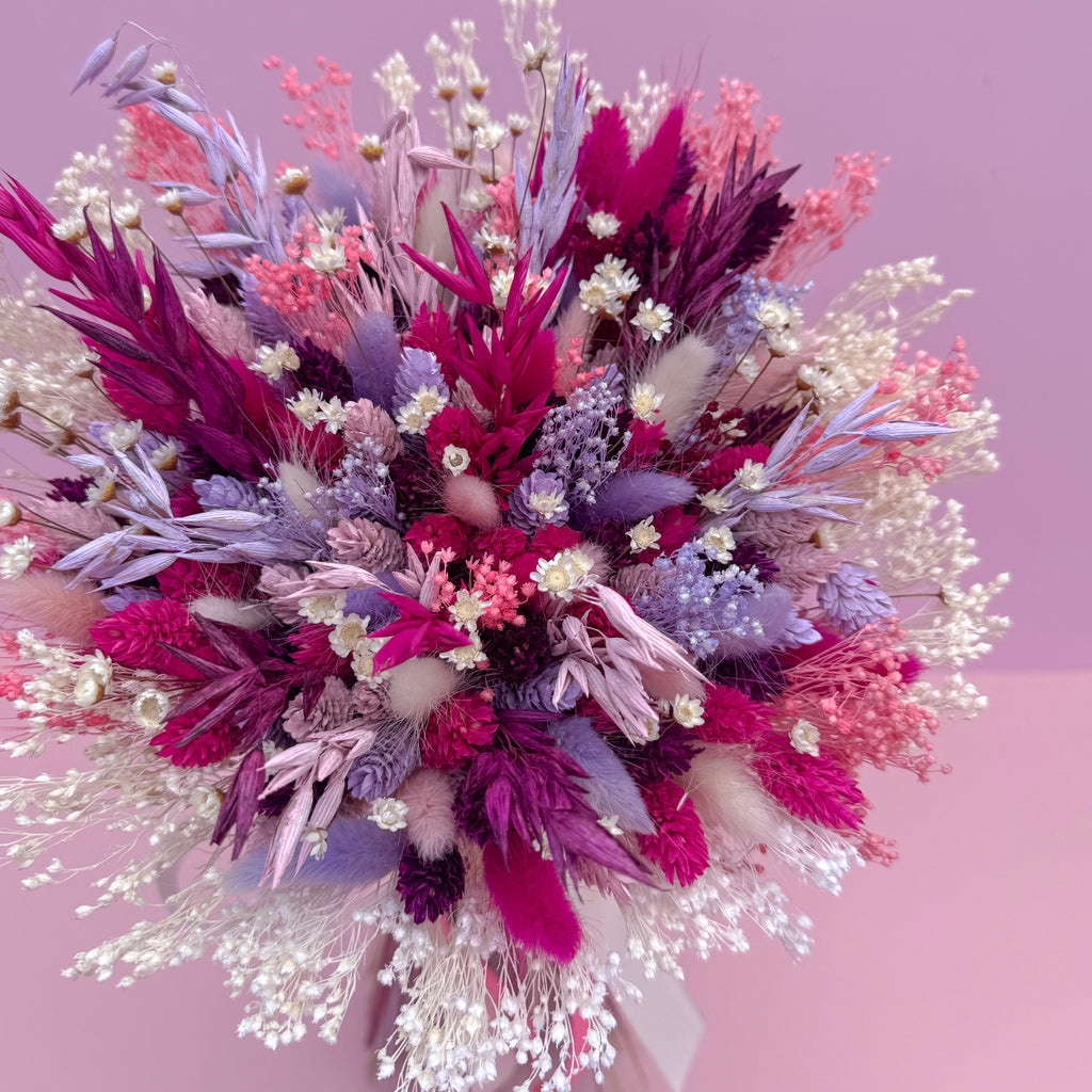 Colorful bouquet of dried flowers on a pink background