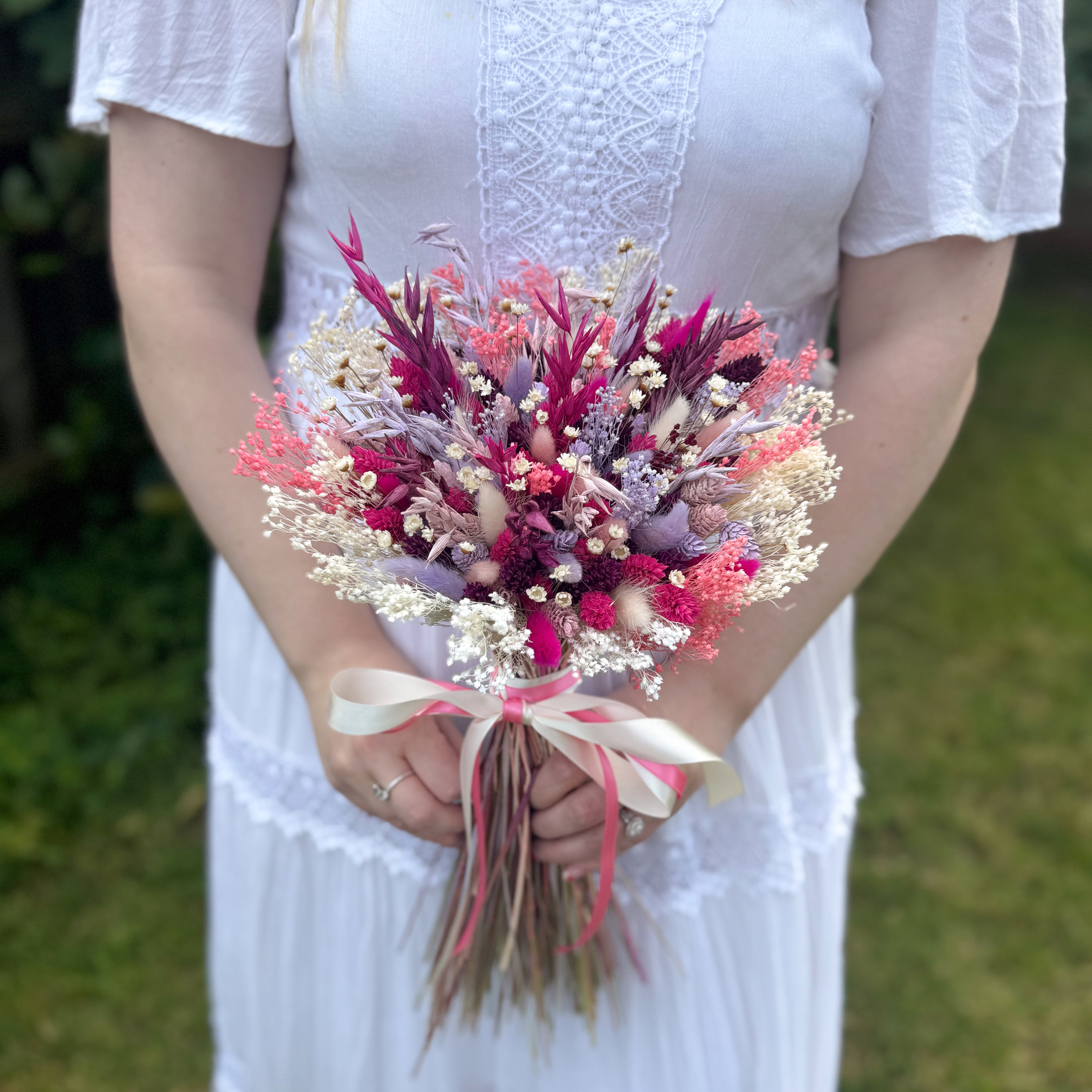 Person holding a bouquet of flowers with a blurred green background