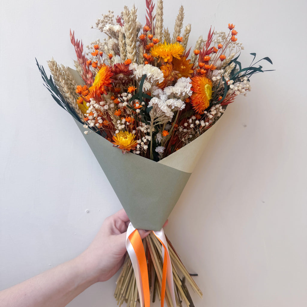 an autumnal dried and preserved flower arrangement with strawflowers, gypsophila and wheat