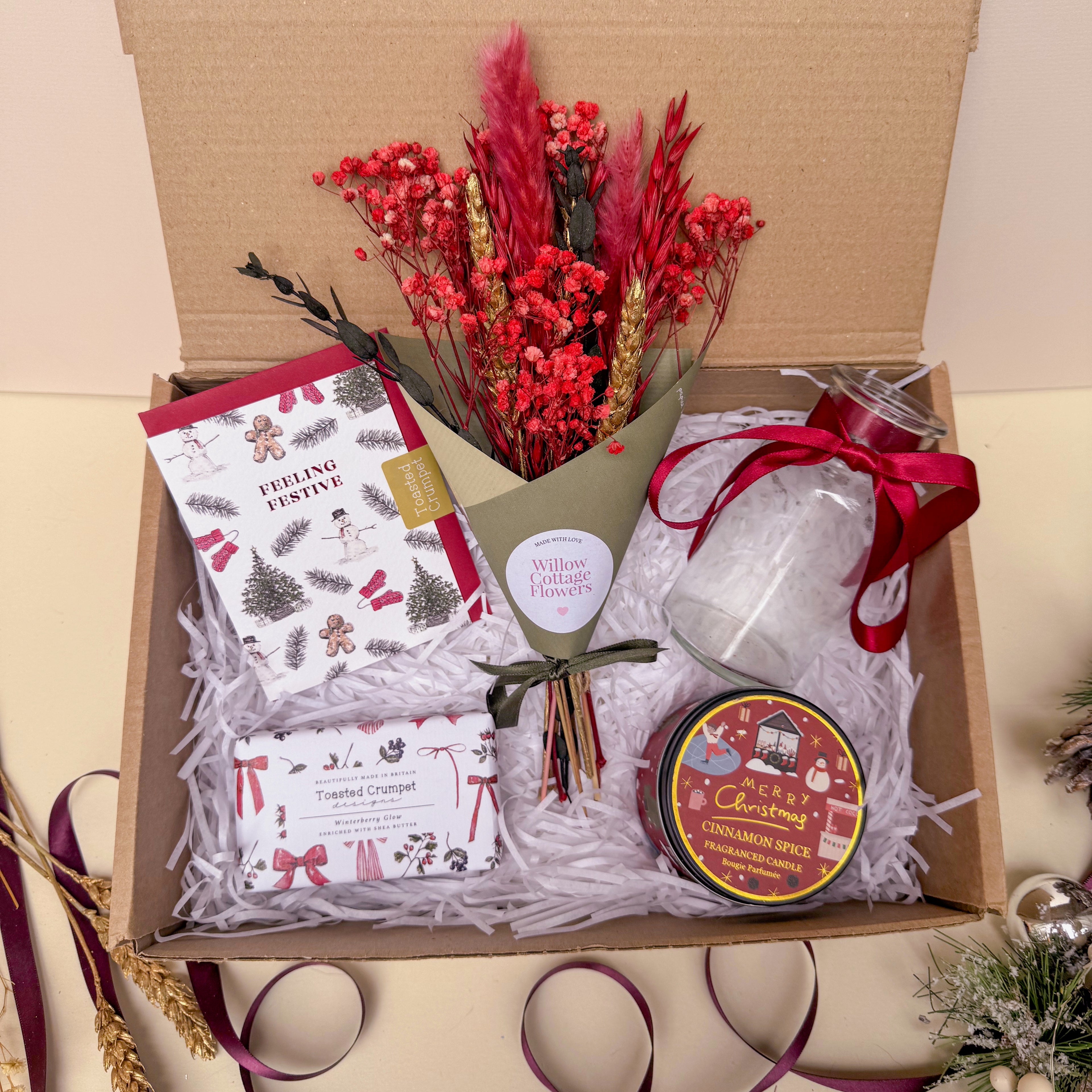 Gift box with Christmas themed items including a bouquet, candle and soap.