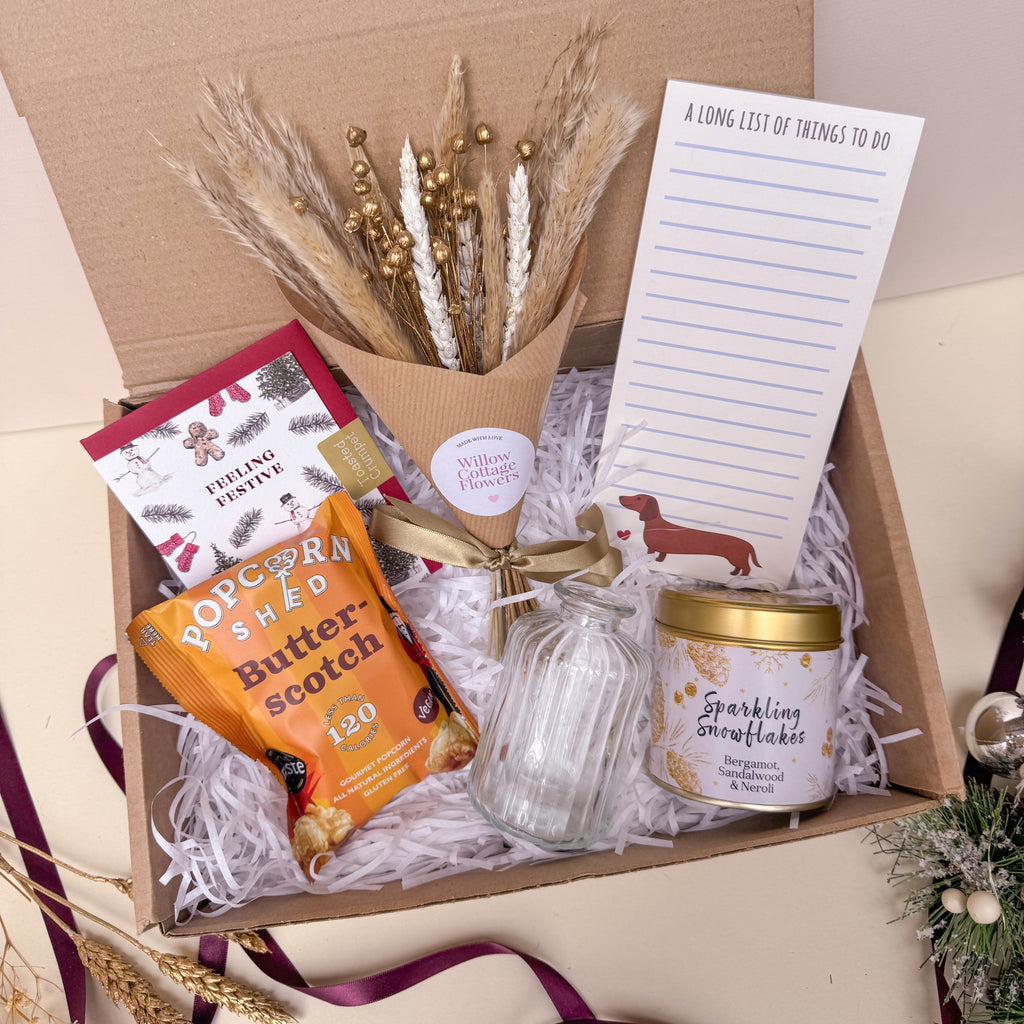 Gift box with popcorn, candle, and decorative items on a beige background for christmas
