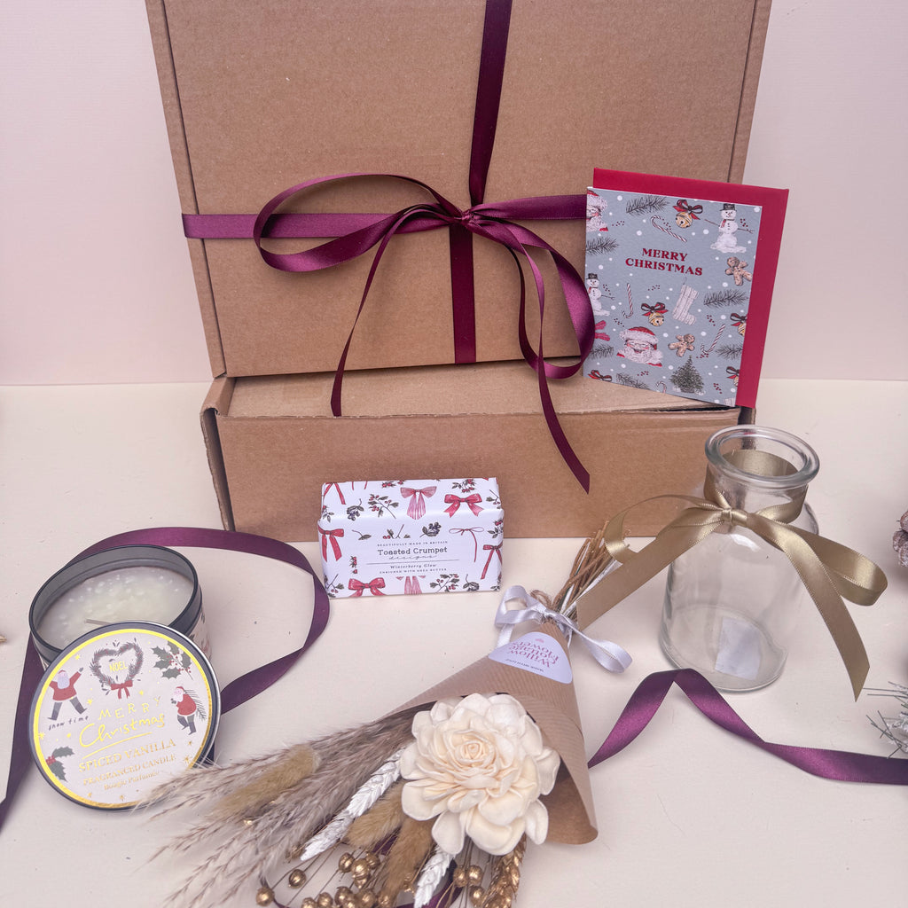 Gift box with festive decorations, candles, and a card on a light background