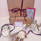 Gift box with festive decorations, candles, and a card on a light background
