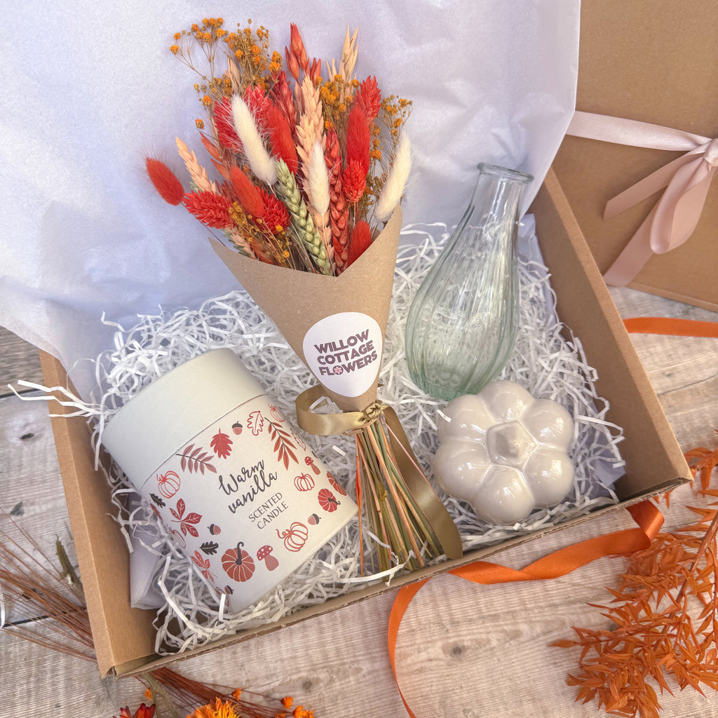 autumn spice gift hamper with dried flower bunch, grey ceramic pumpkin ornament, clear ribbed glass vase and warm vanilla scented candle.