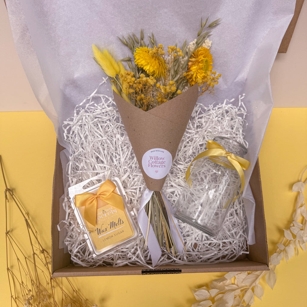 Bouquet of yellow flowers in a box with a card and lemon wax melts on a yellow background