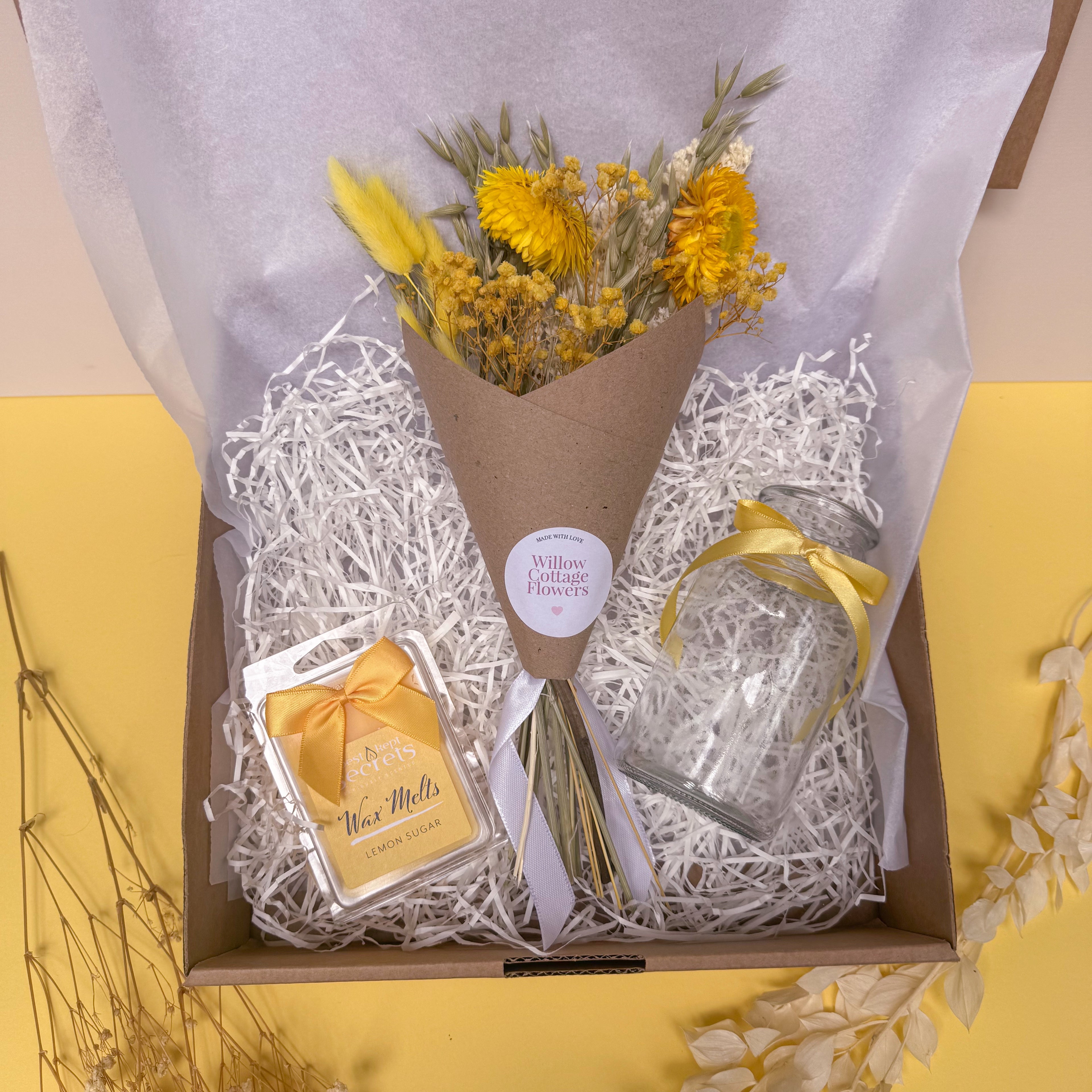 Bouquet of yellow flowers in a box with a card and lemon wax melts on a yellow background