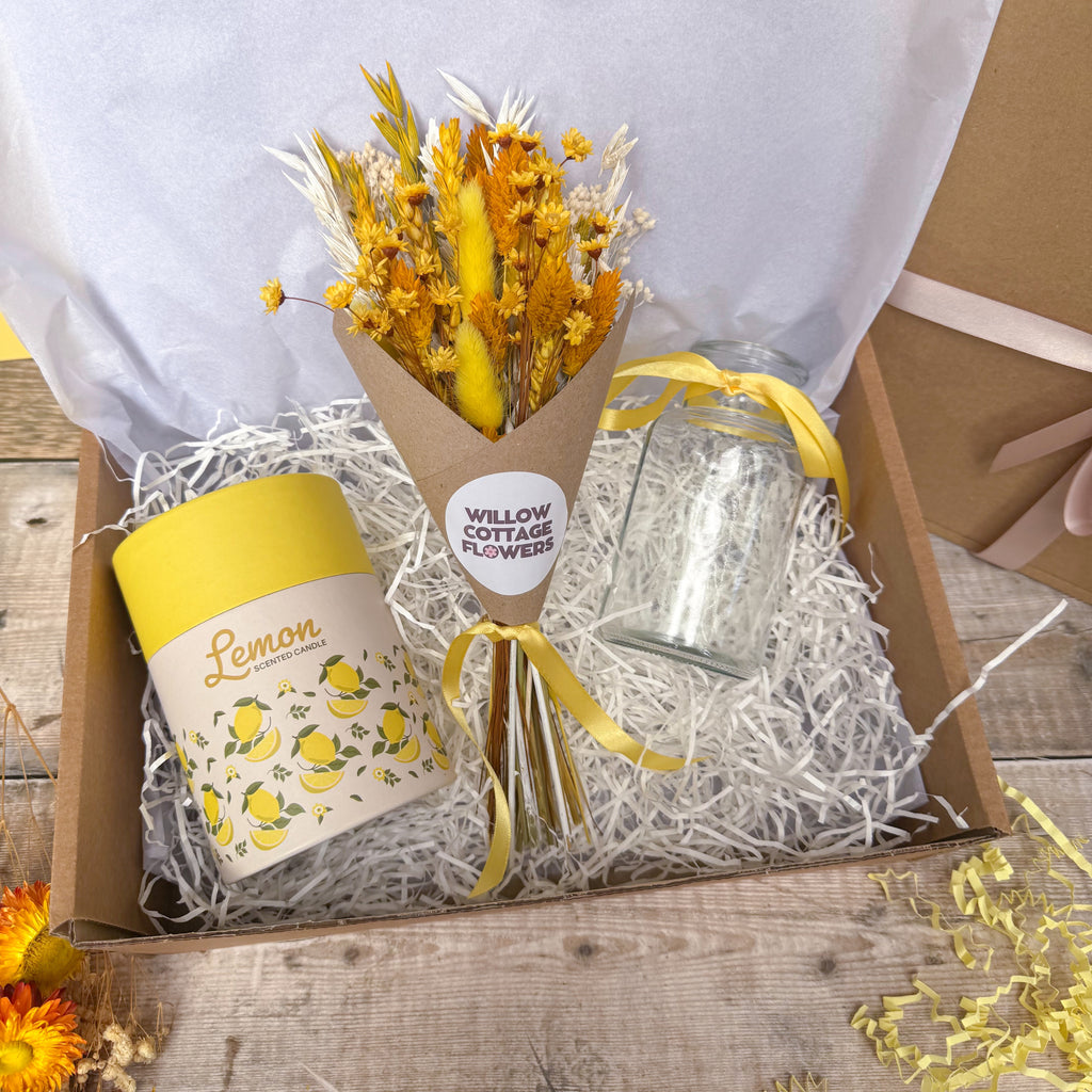 A curated gift box set from Willow Cottage Flowers, featuring a dried yellow flower bouquet in a kraft paper cone, a yellow and white 'Lemon' scented candle, and a clear glass jar, all arranged in white shredded paper inside a wooden box.