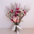 Bouquet of pink and white dried flowers with a white ribbon on a light background