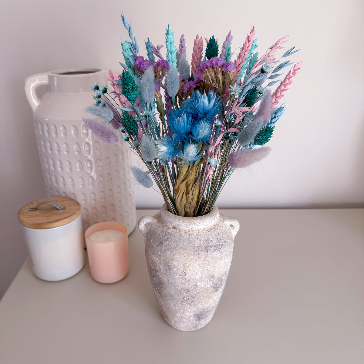 a pastel blue dried flower arrangement displayed in a rustic vase on a table