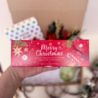 Hand holding a festive candle box with 'Merry Christmas' text against a blurred background.