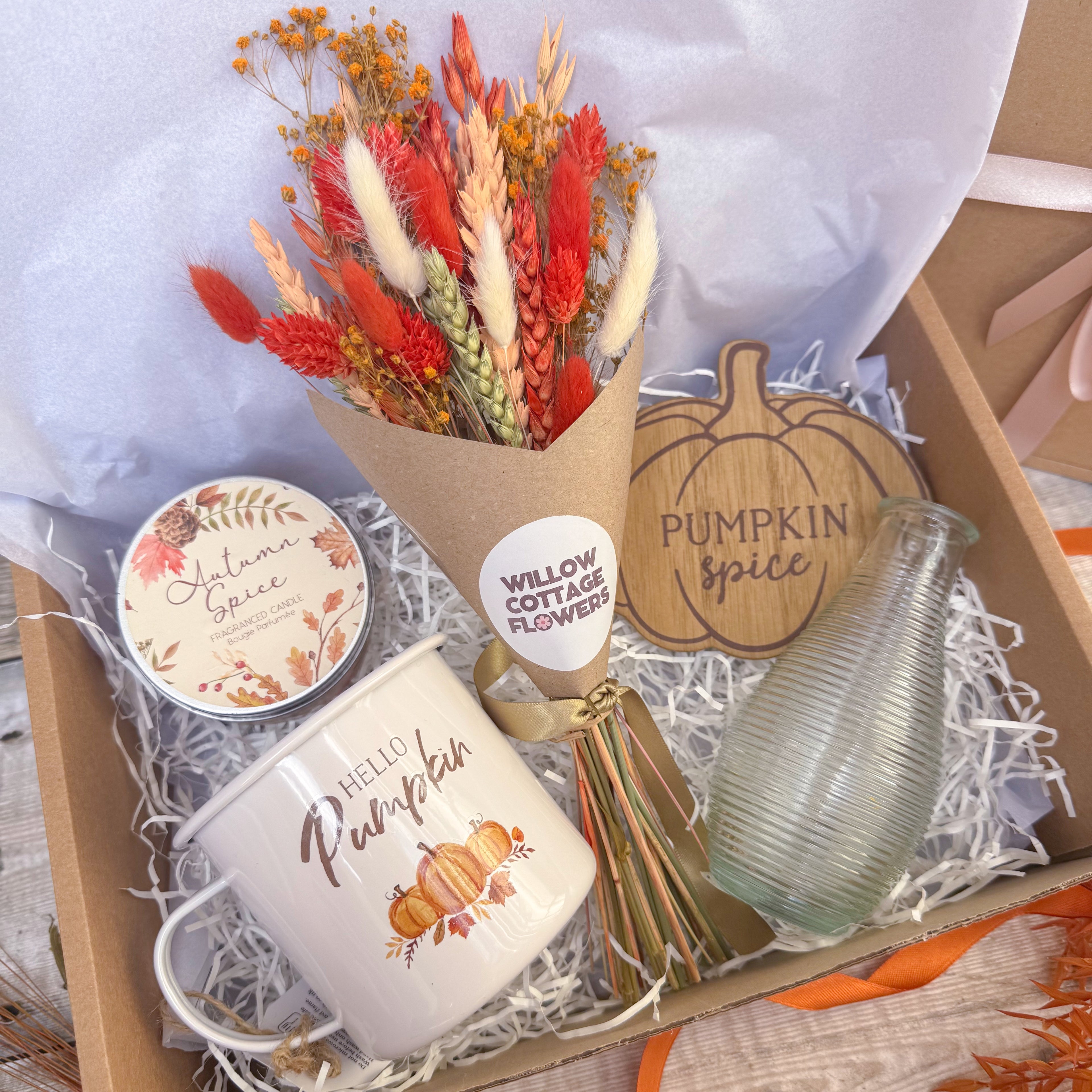 curated autumn gift box with orange dried flowers in brown gift wrap, wooden pumpkin spice coaster, hello pumpkin white enamel mug, autumn spice candle and glass vase