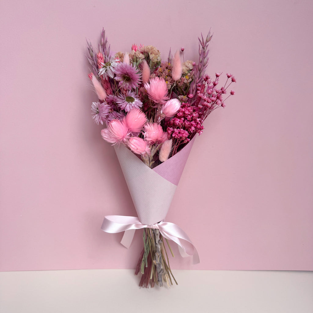 bouquet of pink dried flowers wrapped in pink paper and tied with a pink ribbon