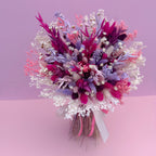 Bouquet of dried flowers in pink, purple, and white on a pink background