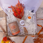 a curated gift box with a pumpkin theme. containing a burnt orange dried flower bouquet, ceramic mouse with pumpkin ornament and pumpkin spice candle