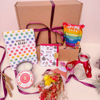 Christmas Gift box with stationery items, popcorn, and a candle on a light pink background