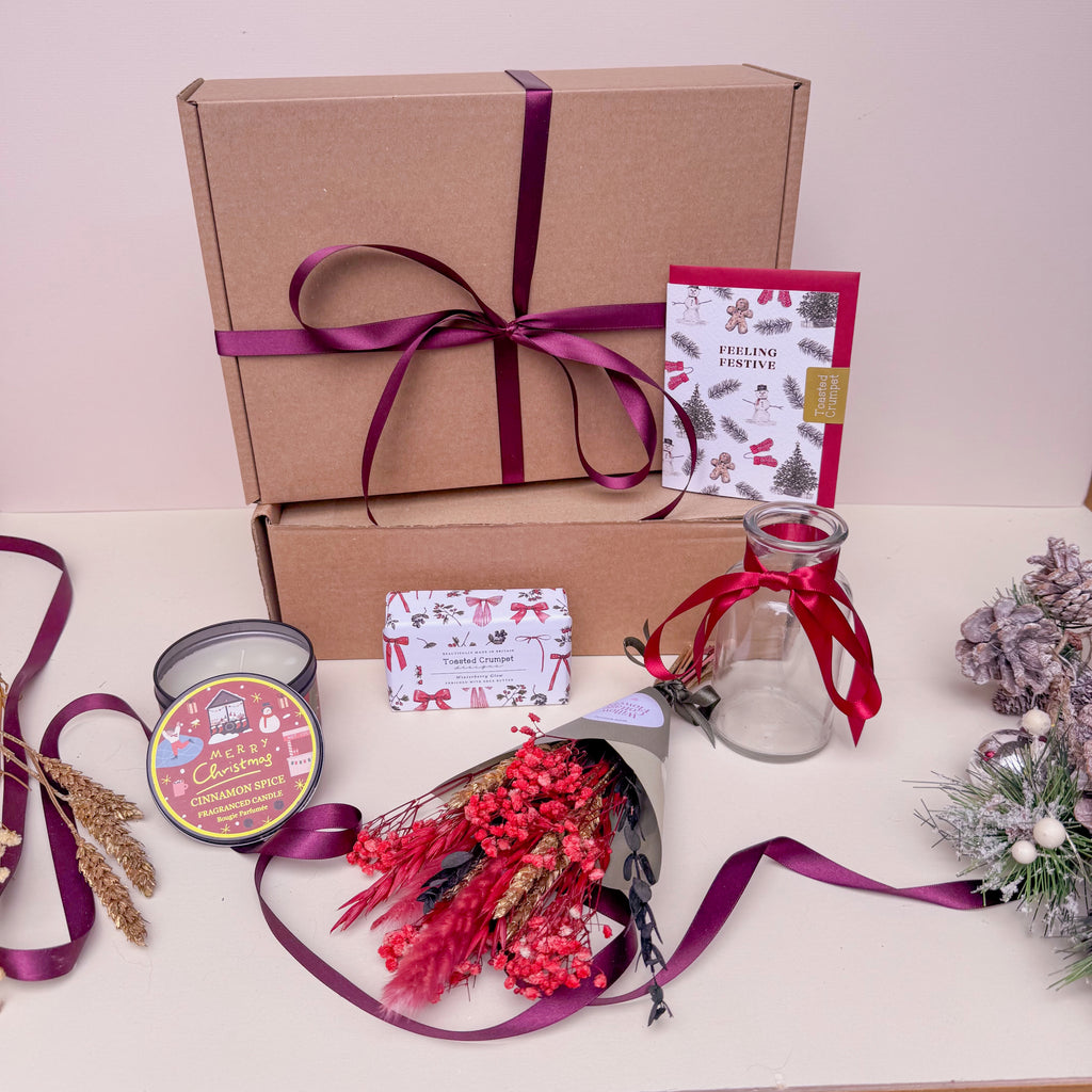 Gift box with a candle and other christmas treats with dried flowers.