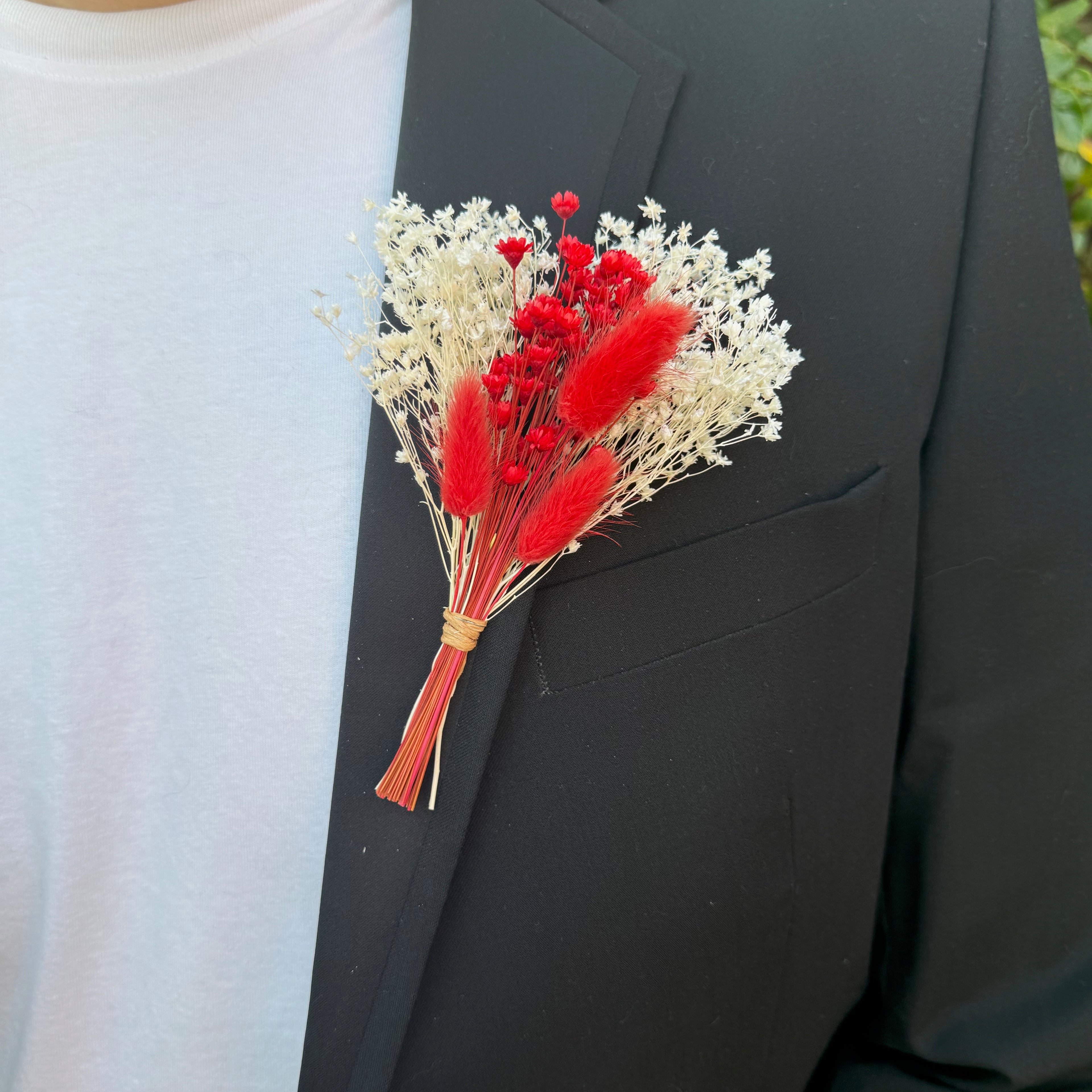red and white dried flower buttonhole on suit