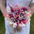 Bouquet of dried flowers held by a person wearing a white dress.