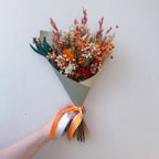 a small flower girl size dried flower bouquet in orange, green and white colours for a wedding.