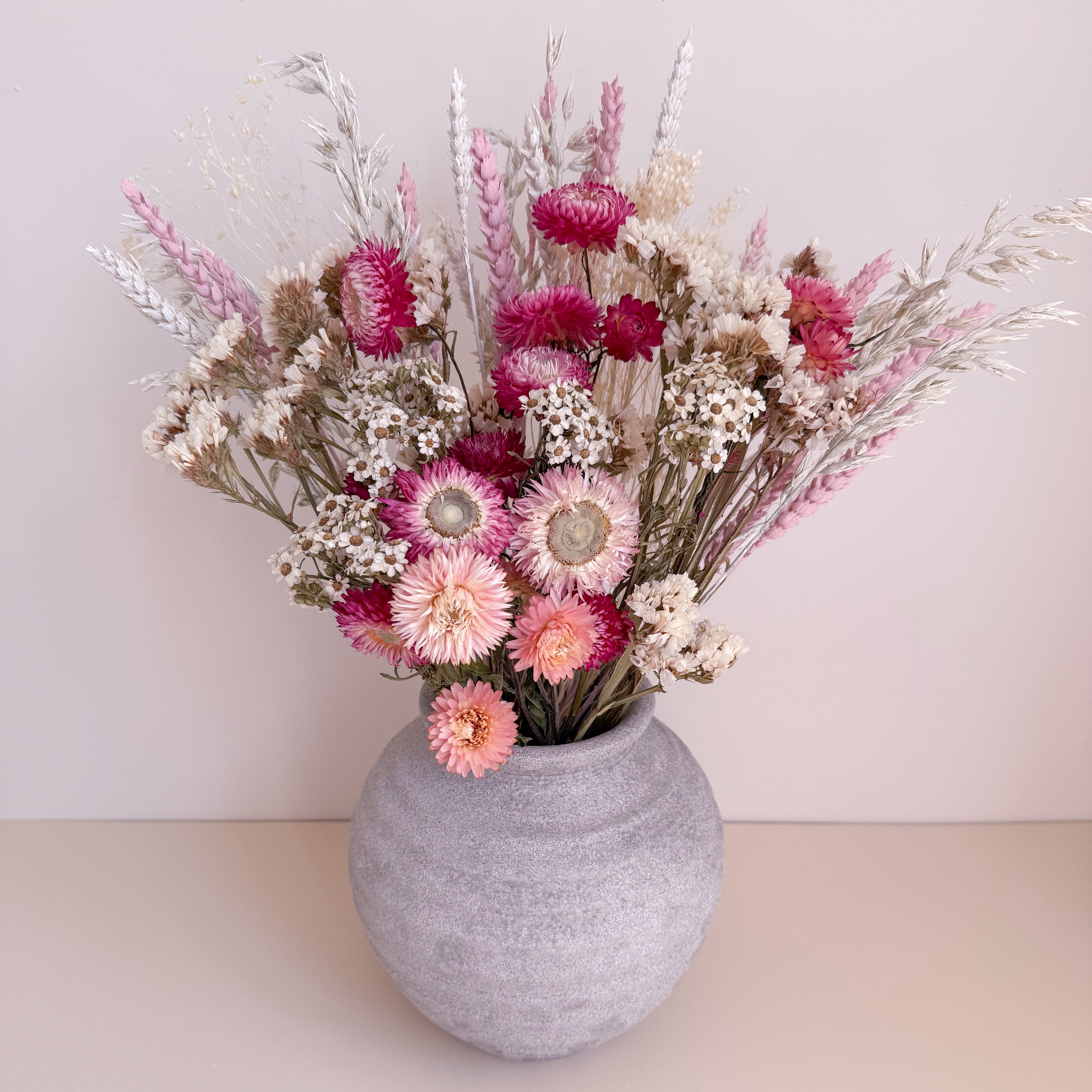 Gray textured vase with a bouquet of pink and white flowers on a light background
