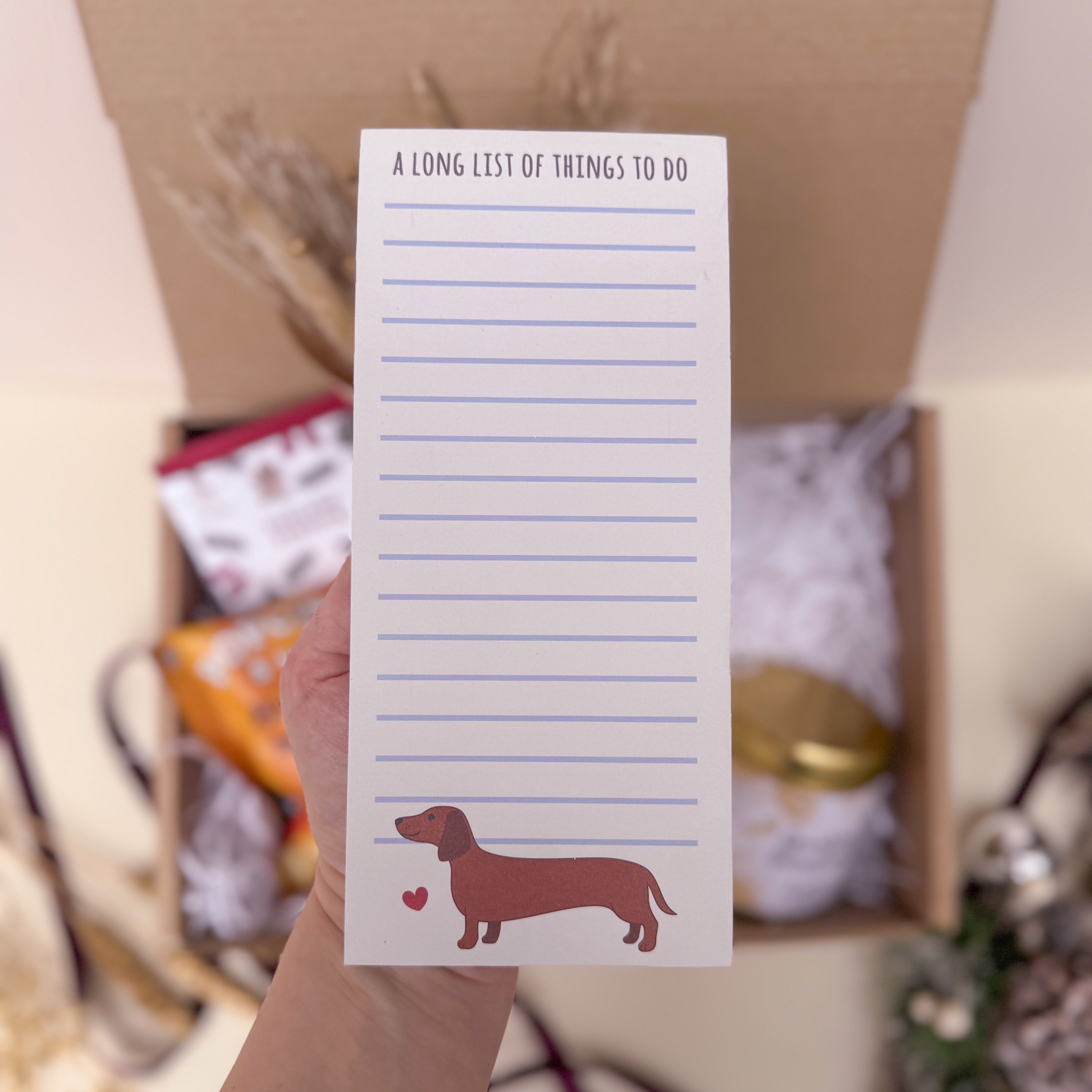 Notepad with a dachshund illustration held in front of a blurred background