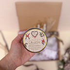 Hand holding a spiced vanilla fragranced candle with a decorative label against a blurred background