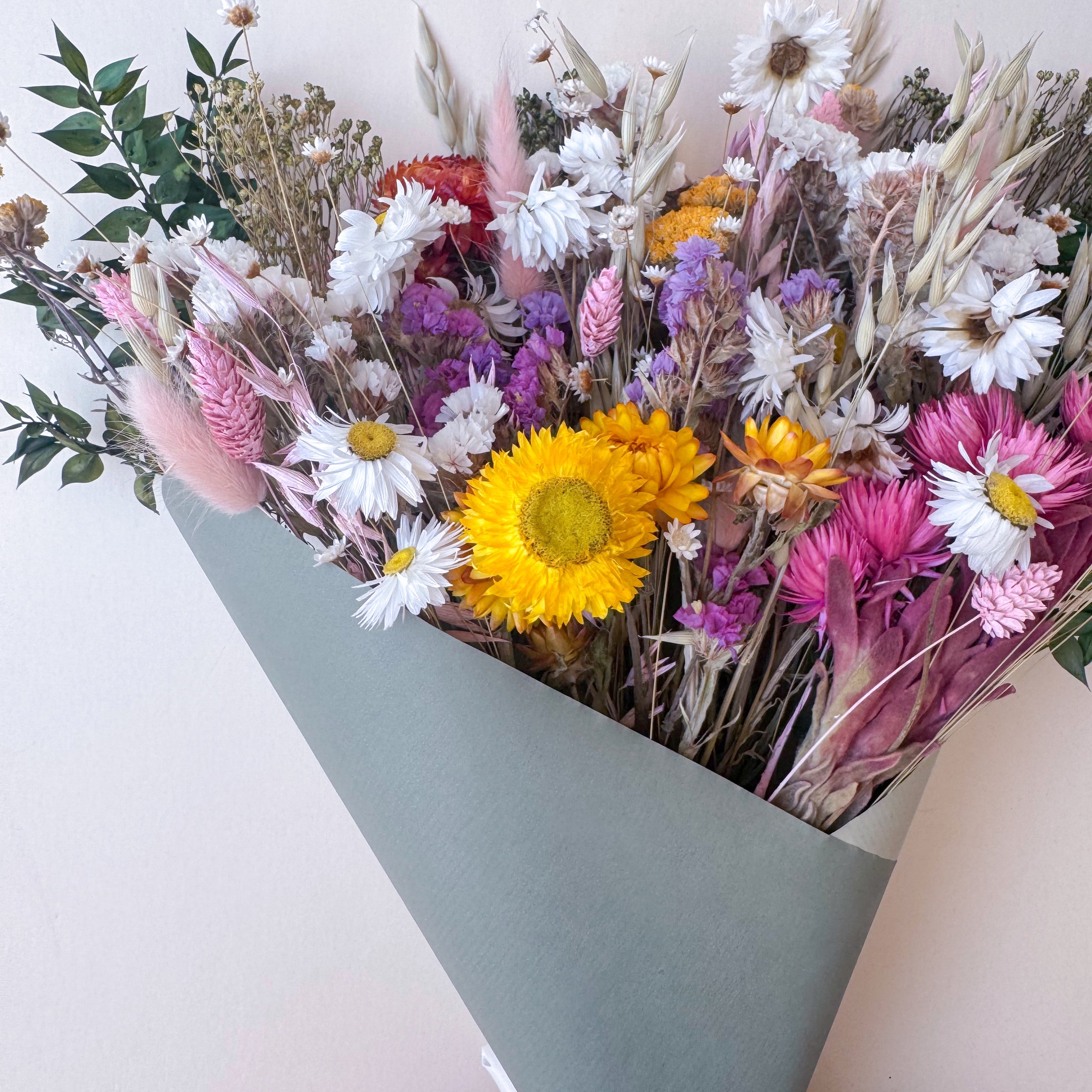 dried daisy arrangement with colourful wildflowers in green paper