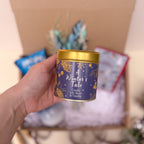 Hand holding a candle labelled 'A Winter's Tale' in cassis, lily rose and vanilla